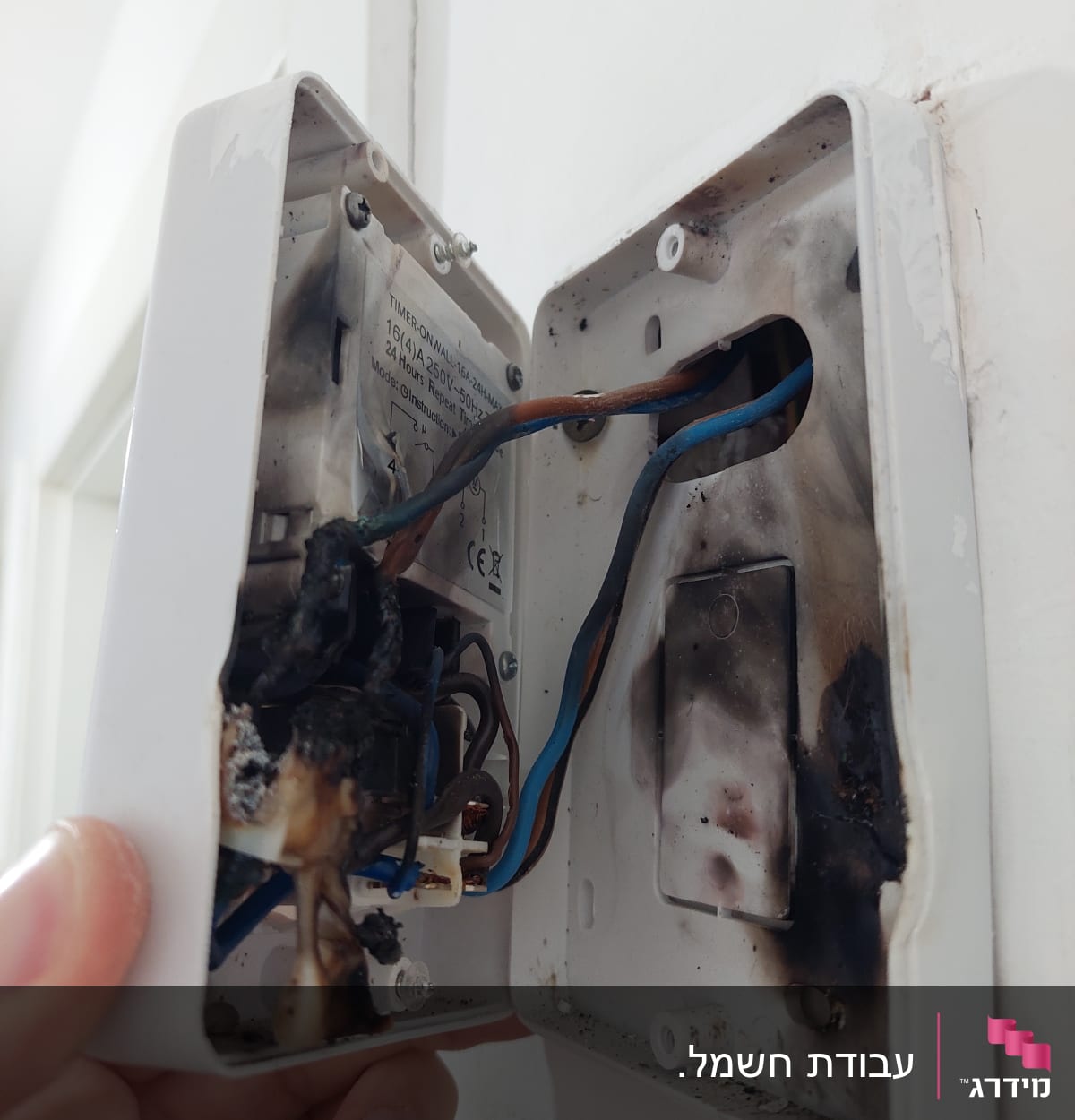 קופסת חשמל פתוחה עם חוטים שרופים ונזק חום